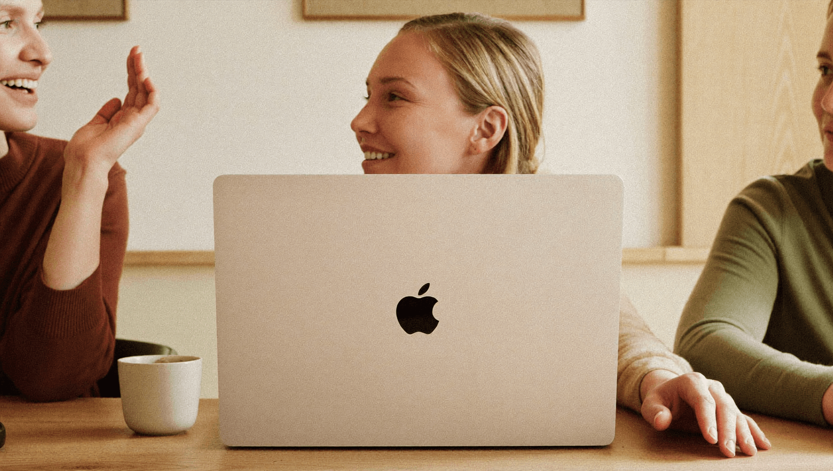 Otwarty laptop przesłania kadr, zza klapy widać osobę w rozmowie.